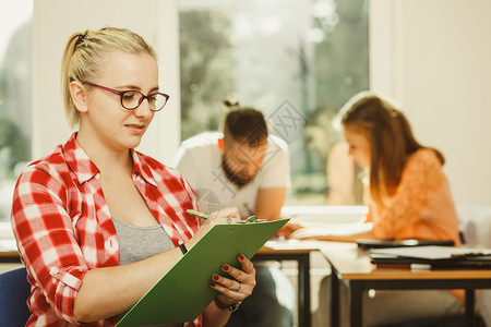 教育高中团队合作和人的概念笔记本坐在学生面前的女在课堂上的同班学图片