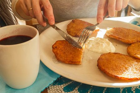 美味土豆煎饼和酸奶油杯茶传统菜女手握餐具美味土豆煎饼和酸奶油图片