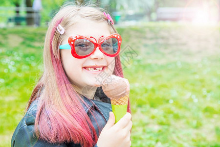 带着墨镜的笑小女孩在公园吃冰淇淋可爱的高清图片素材
