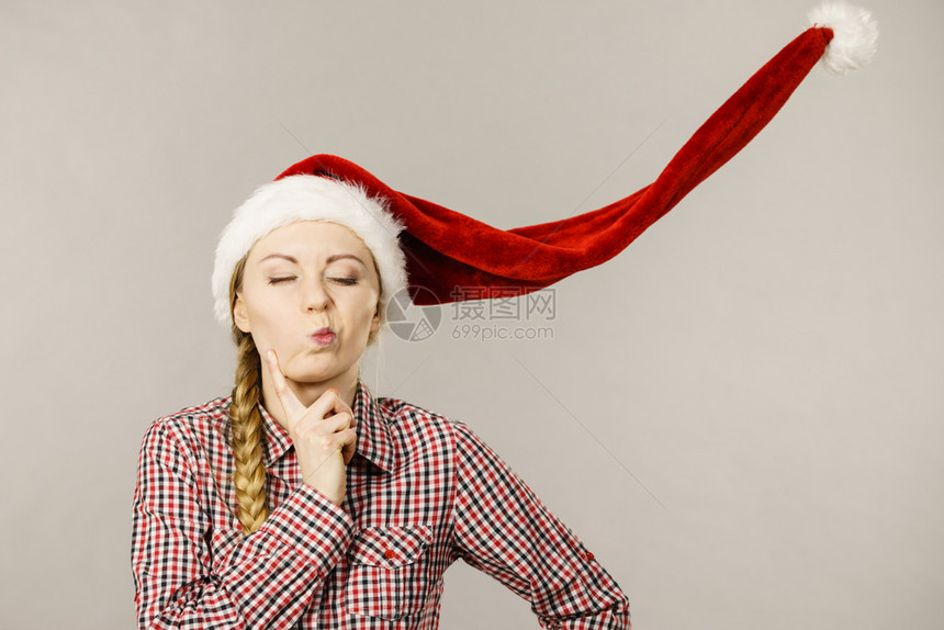 年轻女人有趣的少闭着眼睛戴吹圣达克莱斯帽子圣诞时光工作室拍摄在灰色上有趣的女孩图片