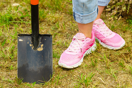 妇女园艺员用铲子挖土田间工作在房子周围妇女用铲子挖土图片