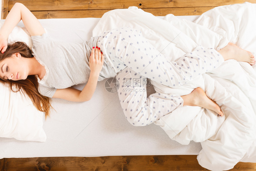 疲惫的睡眠概念疲惫的睡眠女孩处于胎儿状态的年轻女士在床上休息疲惫的睡眠女孩在床上休息图片