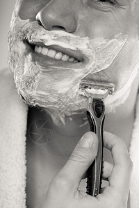男人用剃须刀刮胡子涂有奶油泡沫男人用剃须刀刮胡子男人用奶油泡沫刮脸图片