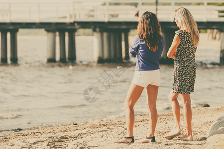 娱乐和休闲有吸引力的中年妇女在沙滩上闲谈女游客在自然水域附近放松两名妇女在海滩上闲谈两名在海滩上闲谈一名在海滩上闲谈一名在海滩上说话高清图片素材