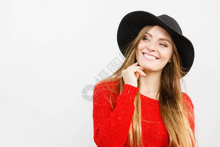 穿着红毛衣黑时装帽在工作室微笑和装扮带着棕色头发和黑帽子微笑的漂亮女孩背景图片