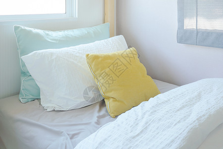 儿童卧室内小床上的黄色和绿枕头图片