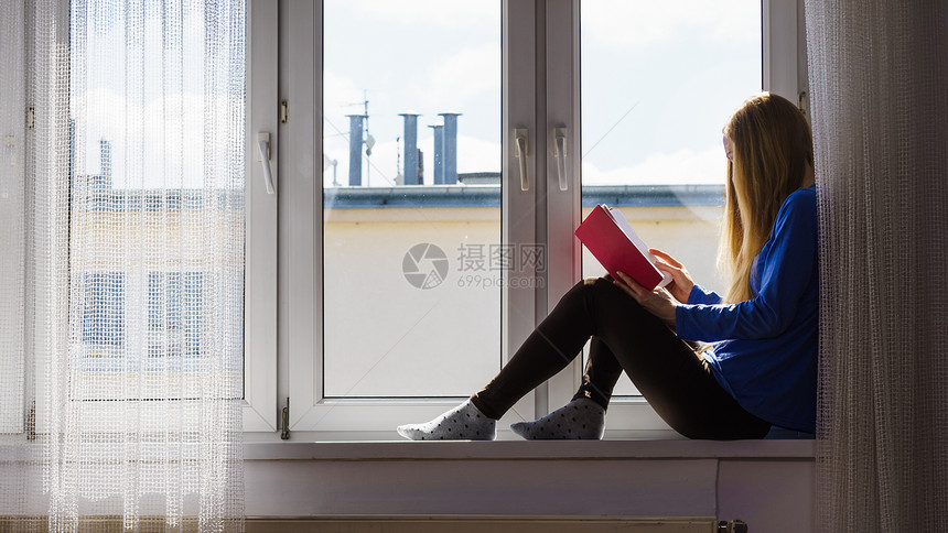 休闲文学和人的概念少女在家里阅读书同时坐在窗边城市风景模糊妇女坐在窗边看书家女孩坐在窗边图片