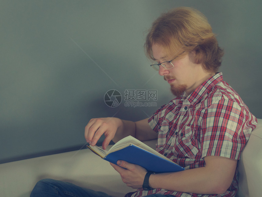 一个人在沙发上看有趣的书享受休闲时间放松概念男人在沙发上放松阅读书图片