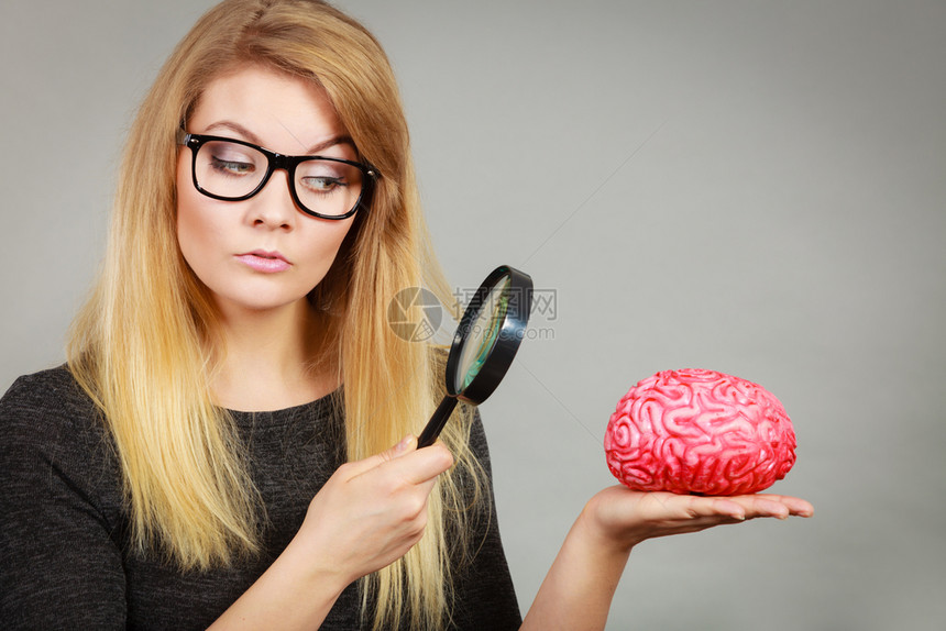 金发女人拿着放大镜调查某事仔细观察假大脑图片