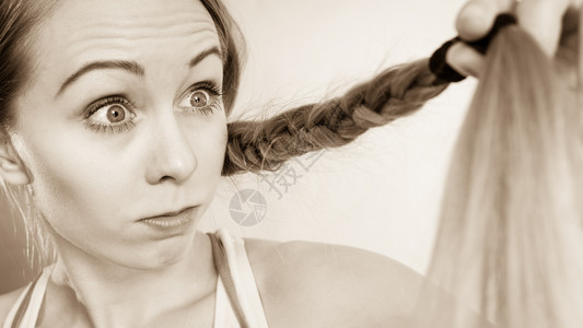 快乐的女士看着她长的金发头看到使用调理器发和概念的积极效果背景图片
