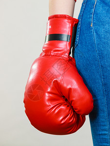 穿着红色拳击手套紧蓝色牛仔裤灰背景穿着拳击手套的妇女图片