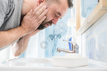 男人在脸上泼水洗澡照顾个人卫生清晨感觉新在浴室洗脸图片