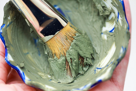 碗中闭合的刷子和绿色粘土面罩碗中闭合的刷子和绿色粘土面罩图片