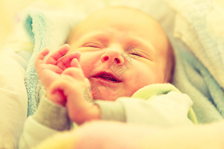 婴儿护理童年概念的美丽小新生婴儿在床上平静地睡觉被毯子环绕面部滑稽的毯子包围小新生婴儿在毯子中平静地睡觉人高清图片素材