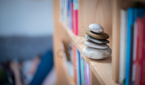 风水在书架上家里的石礁在前景和背上模糊的书本平衡与放松背景图片