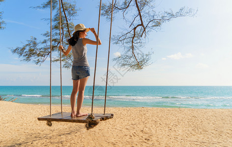 摆动快乐的亚洲女在泰国普吉中午的海洋或自然户外度假旅行中在海滩上摇晃背景