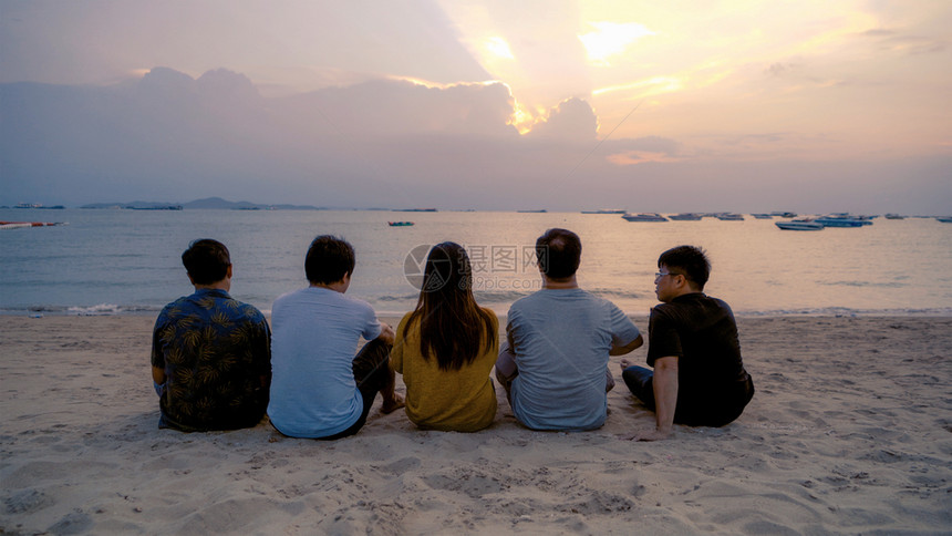 泰国人亚洲朋友串连啤酒瓶子在日落时夏海滩或边庆祝节日图片