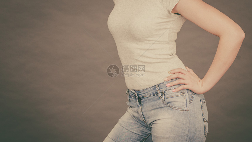 穿紧身牛仔裤和白衬衫展示其身材曲线的女子图片
