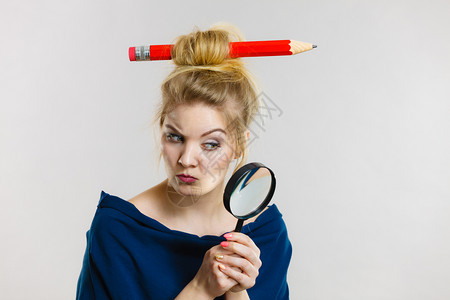 控制办法金发女人拿着放大镜调查一些事情仔细看试图找到解决办法拥有大铅笔在头发上背景