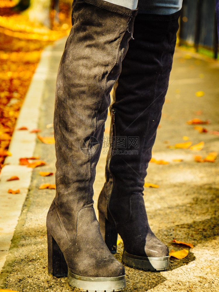 穿着长的黑脚靴高子和牛仔裤秋色时装温暖鞋靴的妇女图片