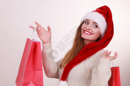 圣诞购物的快乐女孩穿着圣塔帽袋的年轻快乐女人节日庆祝商业快乐休闲概念背景图片
