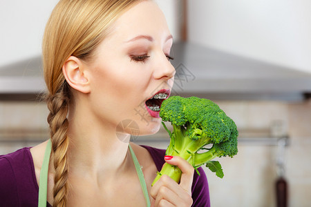 厨房里的女人拿着绿色新鲜花椰菜年轻家庭主妇做饭健康饮食素和人的概念背景图片