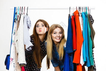 快乐的年轻女子在购物时挑衣服穿尚装快乐的女子买衣服精品店高清图片素材