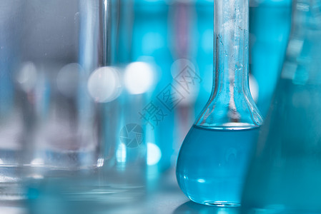 研究人员在实验室化妆品和能源研究中使用玻璃器械和蓝色溶液背景图片