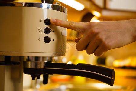 喝自制饮料概念在咖啡机里喝热水的妇女站在厨房里在咖啡机喝热水的妇女图片