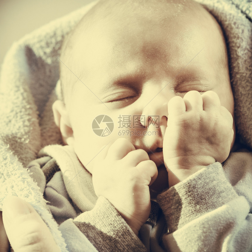 婴儿护理童年概念的美丽小新生婴儿在床上平静地睡觉被毯子环绕面部滑稽的毯子包围小新生婴儿在毯子中平静地睡觉图片