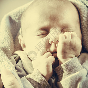 婴儿护理童年概念的美丽小新生婴儿在床上平静地睡觉被毯子环绕面部滑稽的毯子包围小新生婴儿在毯子中平静地睡觉休息高清图片素材