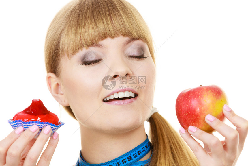 拥有测量胶带的妇女握在手蛋糕和苹果水的选择中试图抵制诱惑做出正确的饮食选择图片