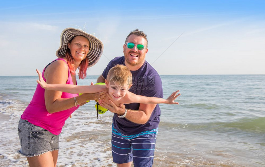 幸福的家庭在海滩上牵着男孩的手图片