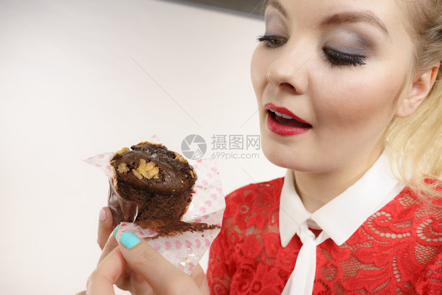 迷人的金发美女手握着味巧克力蛋糕渴望图片