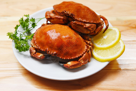 盘子里的煮蟹和柠檬药草以及木制餐桌的香料背景海产食品煮红石蟹沙拉背景图片
