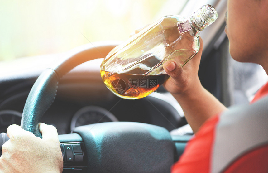 持有酒瓶手并驾驶汽车饮酒的男子图片