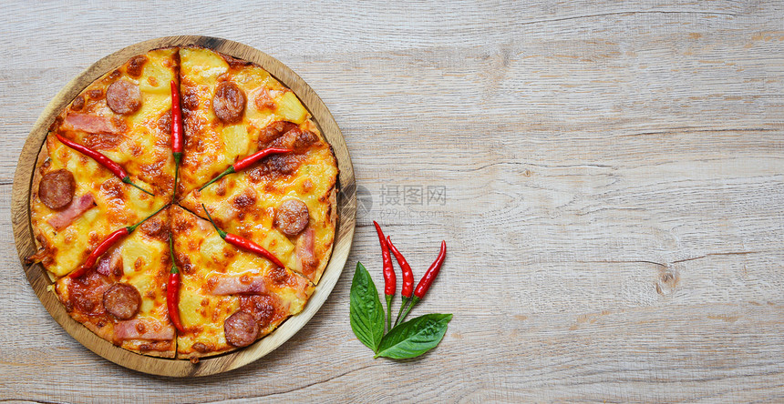 木制餐盘上披萨和辣椒巴西尔叶顶端的风景美味可口的快餐意大利传统比萨奶酪与Mozzarella熏猪肉香肠菠萝火腿加番茄酱复制空间图片