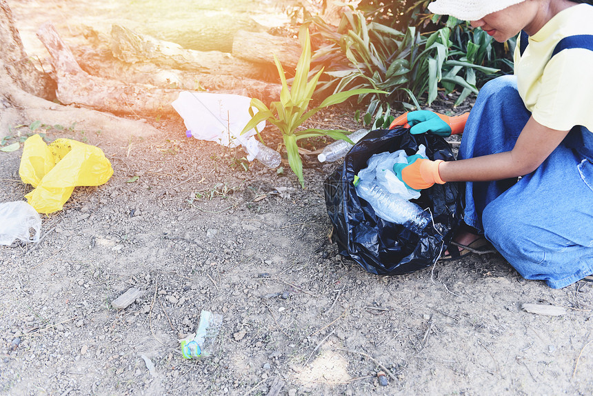 帮助保持自然清洁和从有助于环境的公园回收和废物减少技术中捡垃圾的青年妇女志愿者图片
