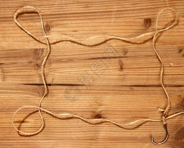 经典的大型钓鱼钩上面绑着粗糙的绳索在木制背景上形成一个简单的框架费希尔高清图片素材
