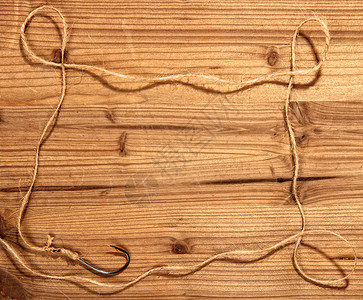 经典的大型钓鱼钩上面绑着粗糙的绳索在木制背景上形成一个简单的框架运动高清图片素材