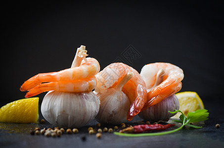 大蒜上的新鲜虾在盘子上海鲜煮开皮虾用辣椒柠檬和黑底煮熟的虾有选择地聚焦于背景图片
