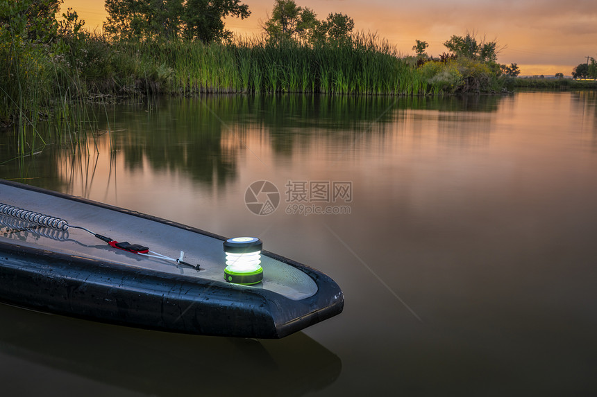 在湖边一个安静的夜晚起立板的尾带着一个小灯笼娱乐概念图片