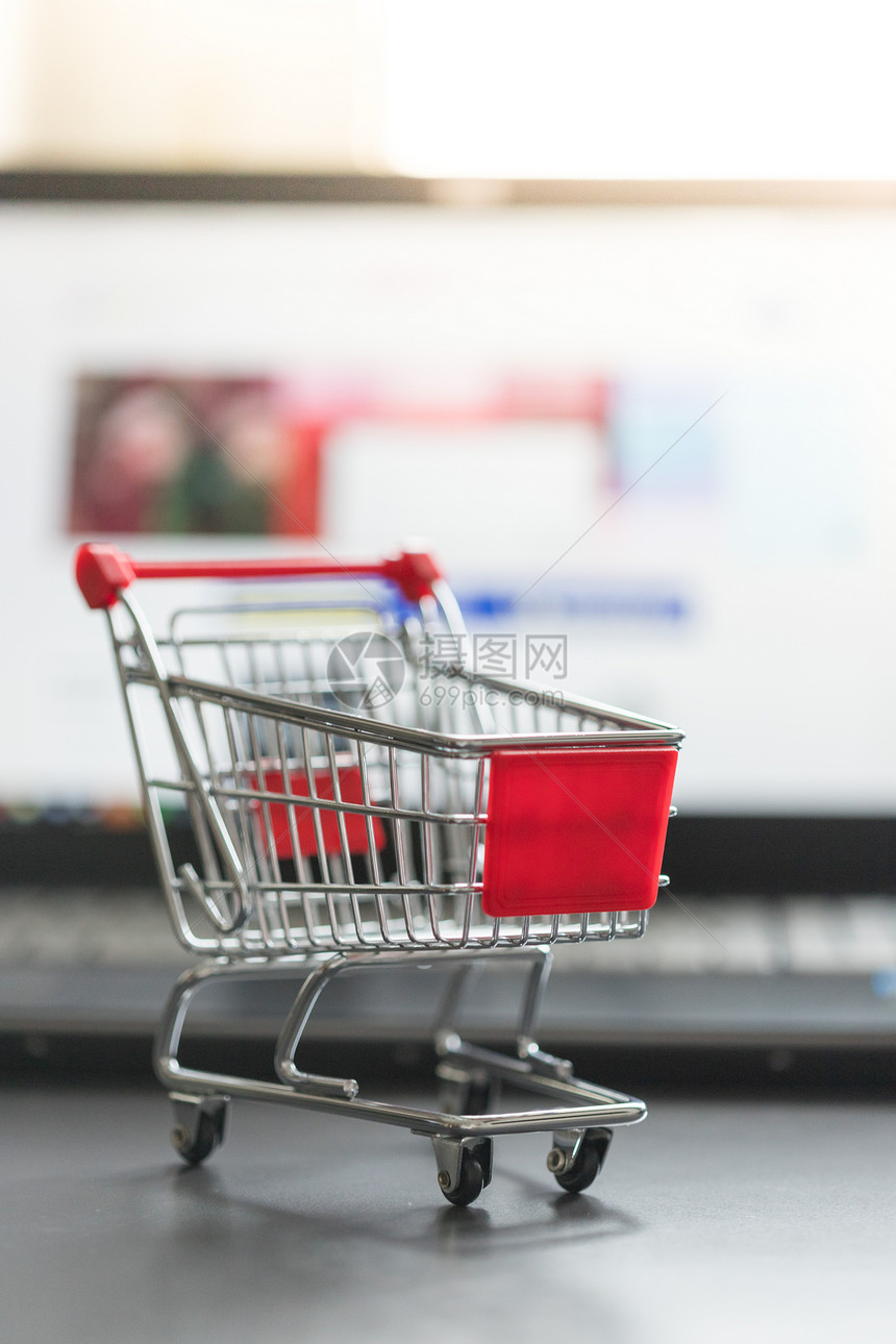 在线购物概念模糊背景的微型购物车手提电脑和鼠标图片
