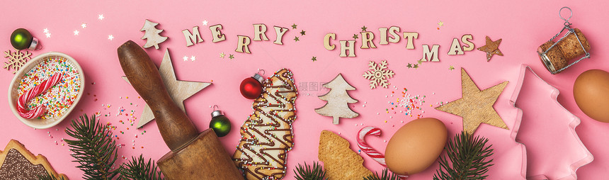 圣诞姜饼干以圣诞树的形状烘烤成份和圣诞快乐以粉红背景的木纸字母写成图片