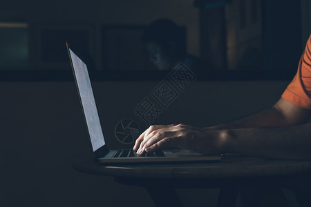 男人在键盘上打字晚在电脑笔记本上工作图片