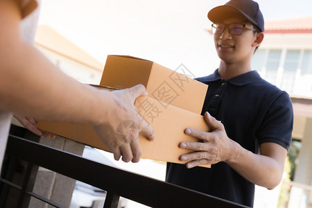 货物工作人员把装有包裹的纸板箱交给收货人手亚洲的高清图片素材