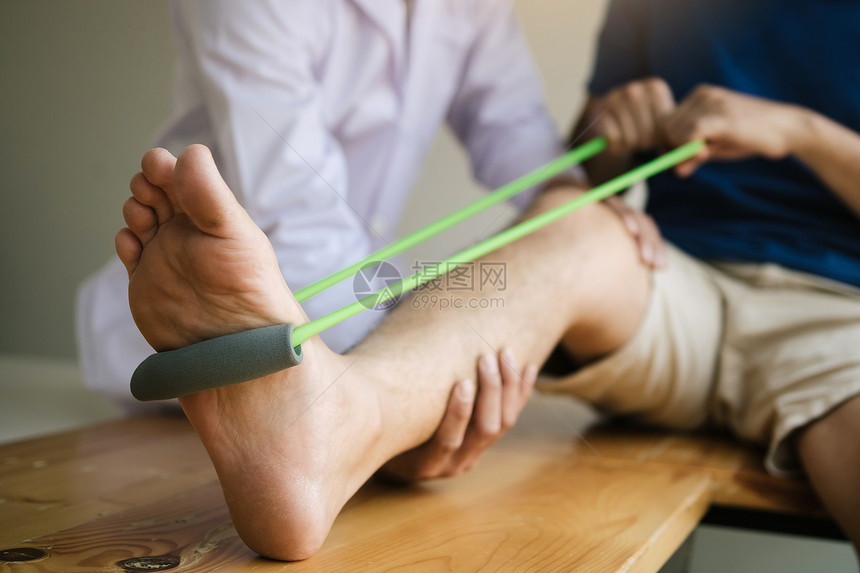 病人用抗药带伸展腿部身体治疗师在诊室帮忙图片