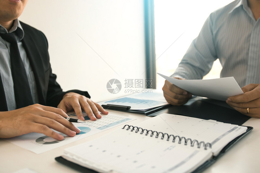 两个商业伙伴关系同事分析战略在办公室预算会议上讨论财务规划图表和公司预算图片