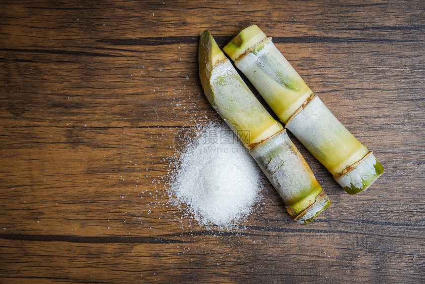 生锈木背景顶视图的甘蔗和白糖图片