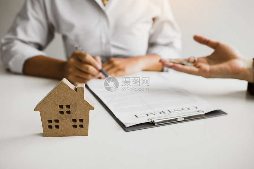 家庭代理商正在寄笔给签订购买新房子合同的客户图片